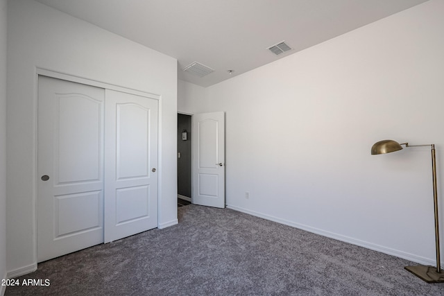 unfurnished bedroom featuring dark carpet and a closet