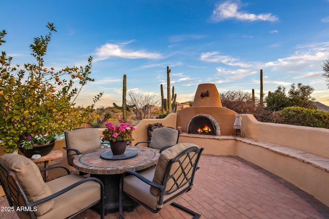 patio terrace at dusk with an outdoor fireplace