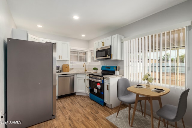 kitchen with light wood-type flooring, white cabinetry, and appliances with stainless steel finishes