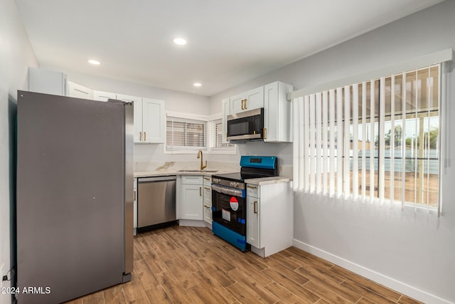 kitchen with stainless steel appliances, white cabinetry, and light hardwood / wood-style floors