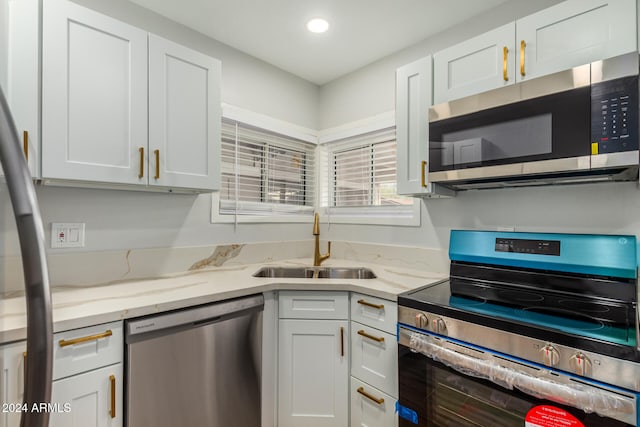 kitchen featuring light stone countertops, sink, white cabinets, and stainless steel appliances