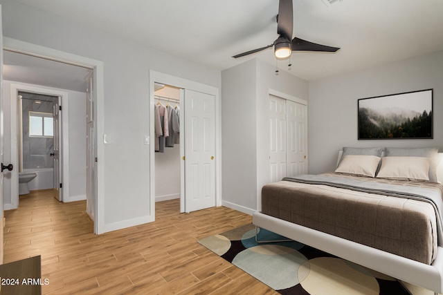 bedroom with light wood-type flooring, two closets, ceiling fan, and connected bathroom