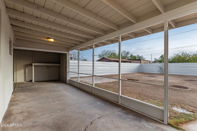 unfurnished sunroom featuring beam ceiling and a wealth of natural light