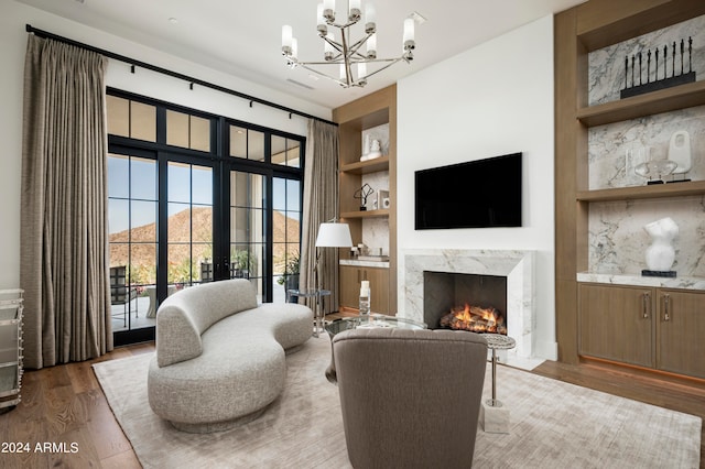 living room featuring an inviting chandelier, dark hardwood / wood-style flooring, a premium fireplace, and french doors