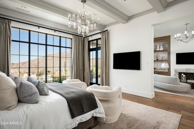 bedroom featuring a mountain view, a fireplace, beamed ceiling, wood-type flooring, and a chandelier