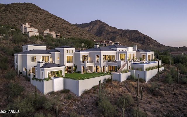 20958 N 112th St, Scottsdale, AZ 85255 - back of house at dusk featuring a mountain view, stucco siding, and a balcony