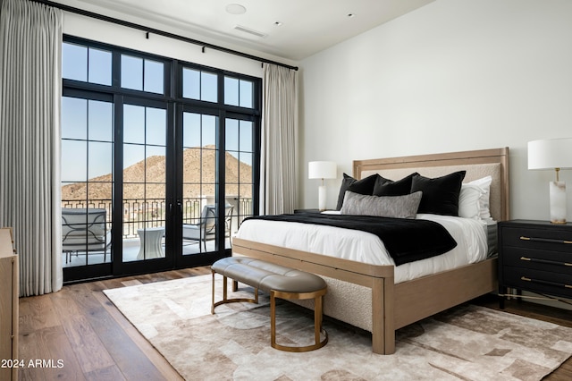 bedroom with hardwood / wood-style floors, a mountain view, access to outside, and french doors