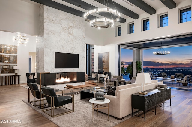 living room featuring a fireplace, a towering ceiling, hardwood / wood-style flooring, and beamed ceiling