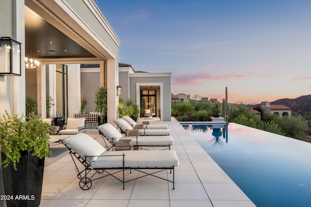 pool at dusk featuring a patio