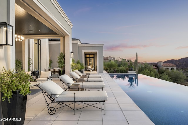 20958 N 112th St, Scottsdale, AZ 85255 - patio terrace at dusk with a patio area, an infinity pool, and an outdoor living space