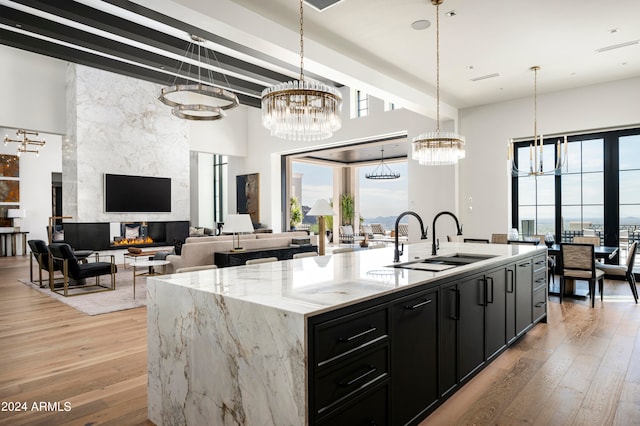 kitchen with a large fireplace, sink, pendant lighting, plenty of natural light, and an island with sink