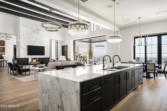 20958 N 112th St, Scottsdale, AZ 85255 - kitchen featuring a chandelier, dark cabinets, plenty of natural light, light wood-style flooring, and a high ceiling