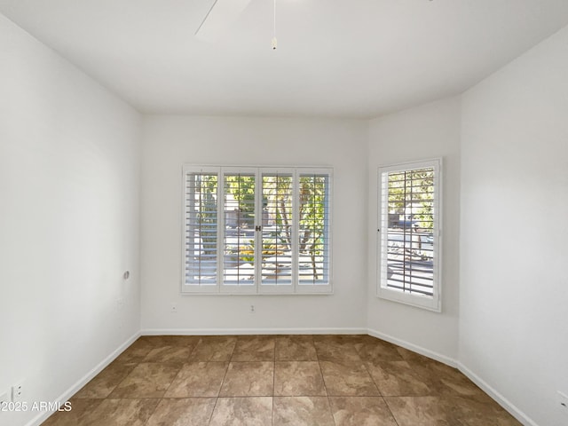 unfurnished room featuring ceiling fan, tile patterned floors, and baseboards