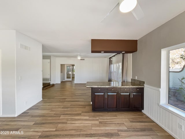 kitchen with light wood finished floors, visible vents, ceiling fan, open floor plan, and dark brown cabinets