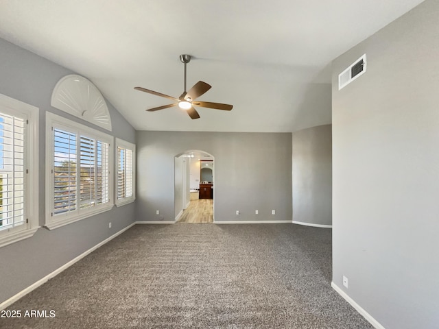 empty room with light carpet, visible vents, arched walkways, a ceiling fan, and vaulted ceiling