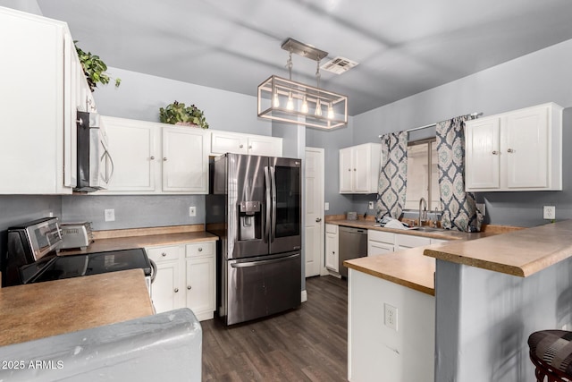 kitchen with appliances with stainless steel finishes, white cabinets, visible vents, and dark wood-type flooring