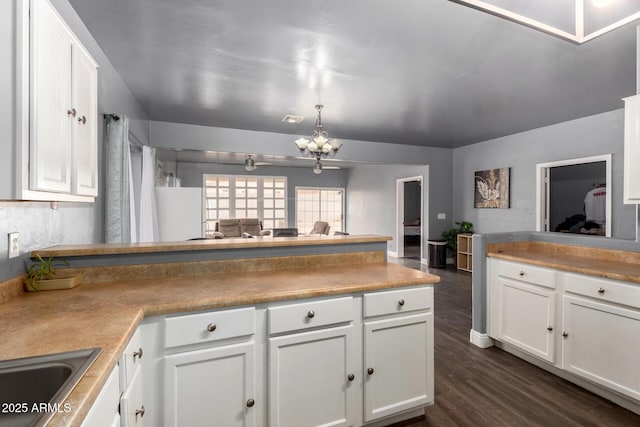 kitchen featuring a chandelier, a peninsula, white cabinetry, open floor plan, and dark wood-style floors