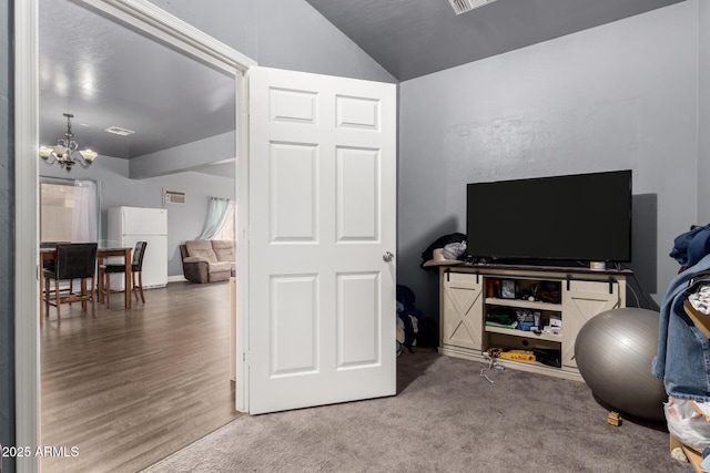 carpeted office featuring an inviting chandelier, visible vents, vaulted ceiling, and wood finished floors