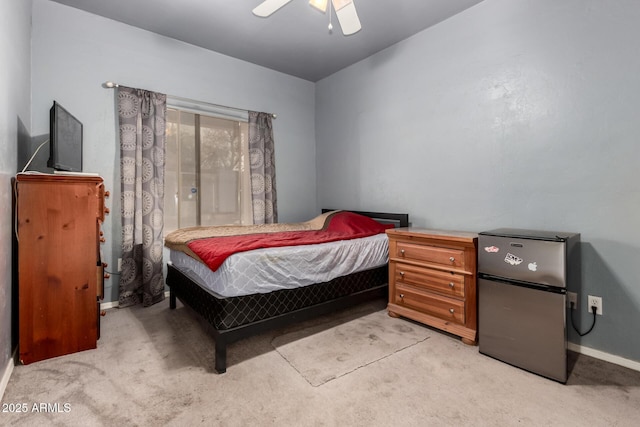 bedroom featuring a ceiling fan, freestanding refrigerator, light carpet, and baseboards