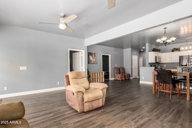 living area featuring dark wood-style flooring, baseboards, and ceiling fan with notable chandelier