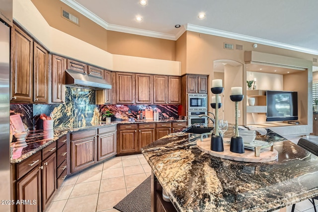 kitchen with dark stone countertops, a large island with sink, and appliances with stainless steel finishes