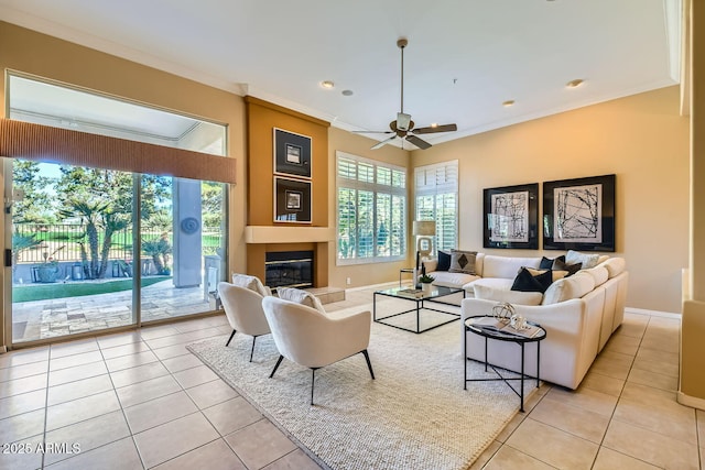 tiled living room featuring ornamental molding, a large fireplace, and ceiling fan