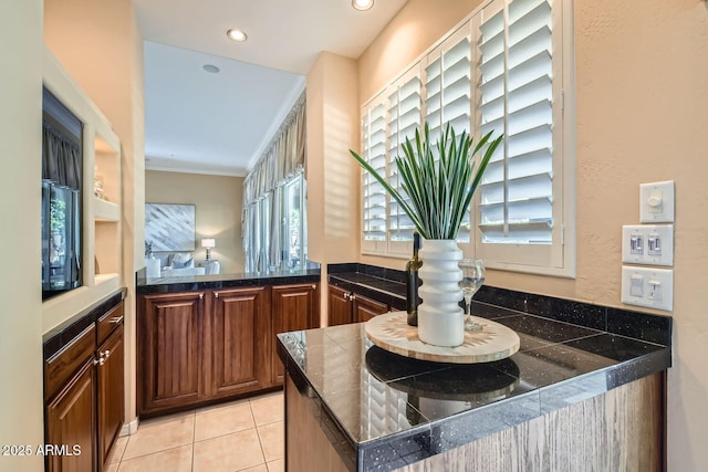 kitchen with crown molding, a healthy amount of sunlight, light tile patterned floors, and kitchen peninsula