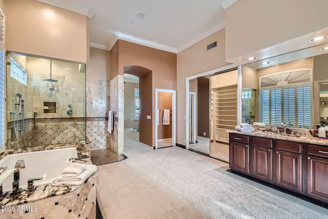 bathroom featuring vanity, crown molding, shower with separate bathtub, and a towering ceiling