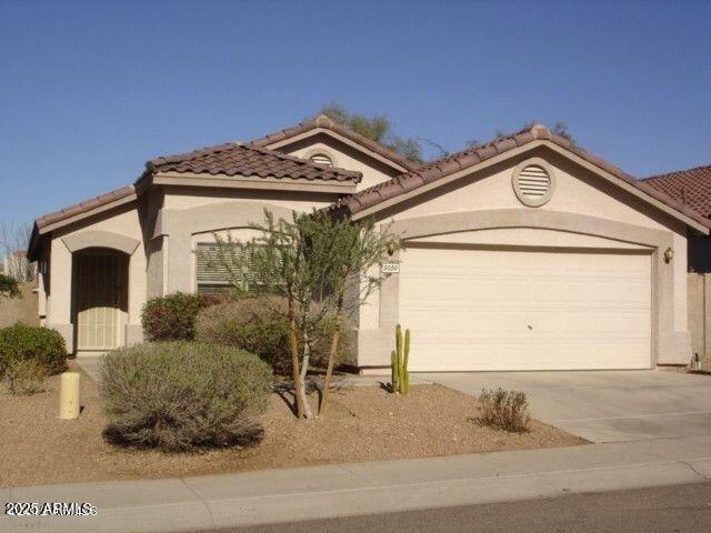 mediterranean / spanish home with driveway, a tiled roof, an attached garage, and stucco siding