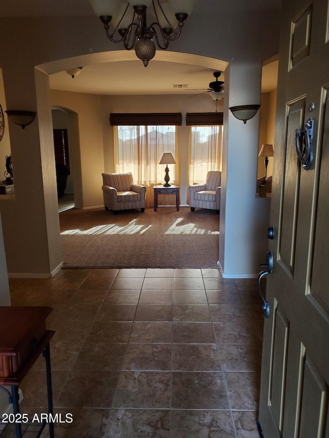 carpeted foyer featuring ceiling fan with notable chandelier