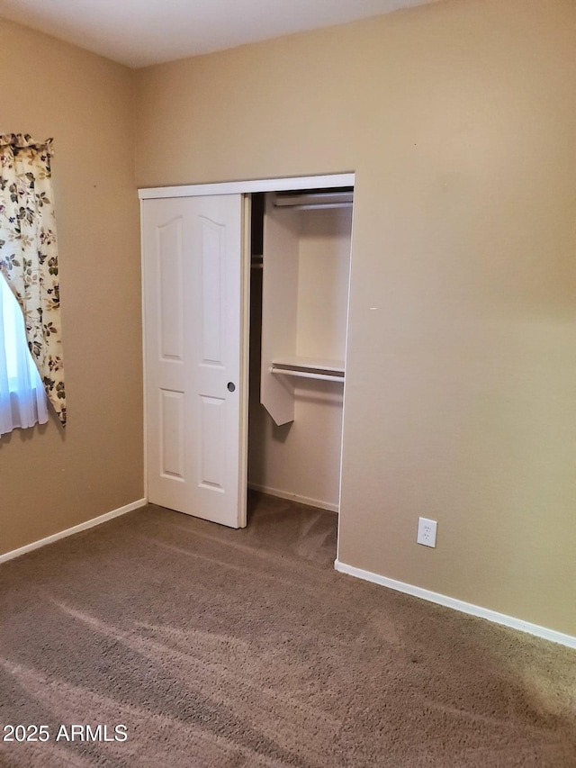 unfurnished bedroom with a closet and dark colored carpet