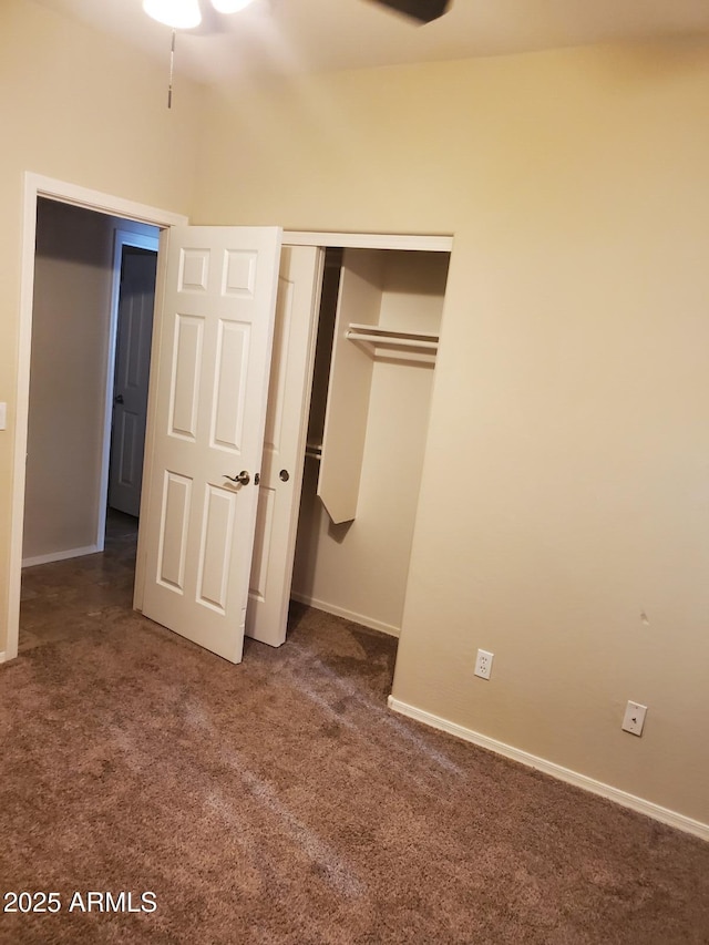 unfurnished bedroom with dark carpet and a closet