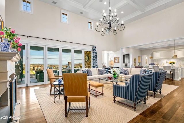 living room with beam ceiling, a notable chandelier, light hardwood / wood-style floors, and a wealth of natural light