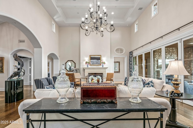 living room featuring a towering ceiling, a chandelier, and wood-type flooring