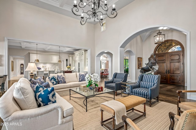 living room with beam ceiling, coffered ceiling, light hardwood / wood-style flooring, and an inviting chandelier