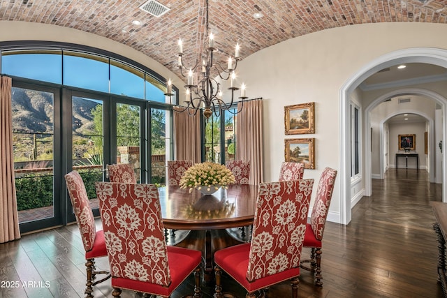 dining area with dark wood-type flooring, brick ceiling, a notable chandelier, lofted ceiling, and crown molding