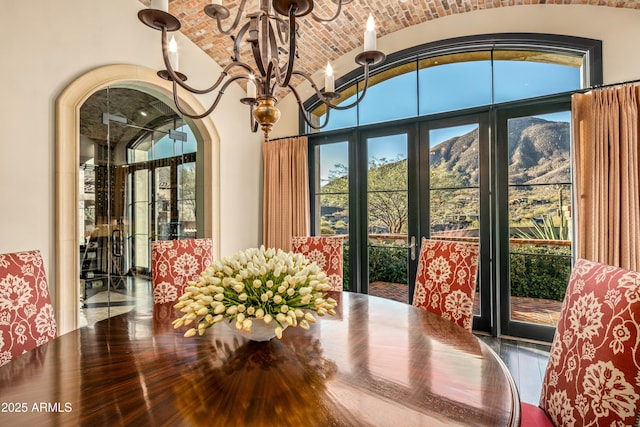 dining area with brick ceiling, french doors, a mountain view, lofted ceiling, and an inviting chandelier