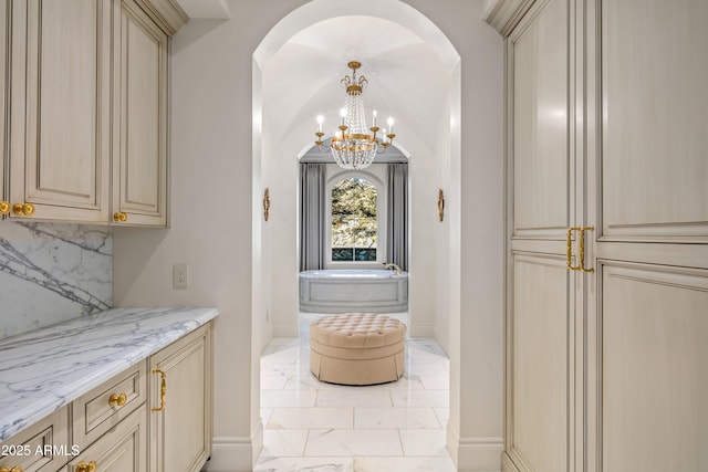 bar with an inviting chandelier, tasteful backsplash, and light stone countertops