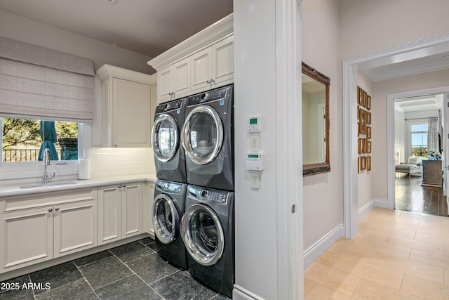 laundry area featuring sink, stacked washer / drying machine, and cabinets