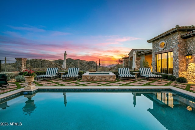 pool at dusk featuring an in ground hot tub