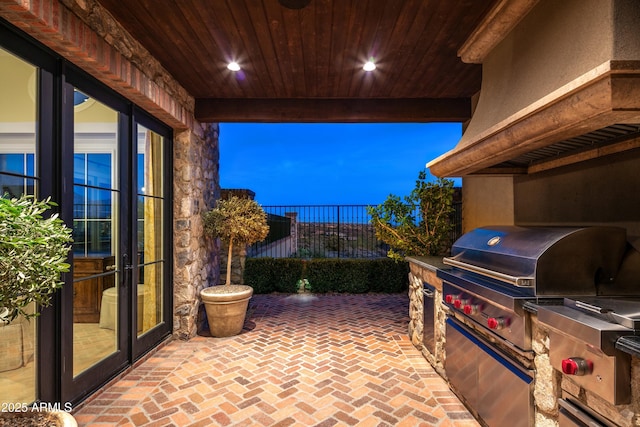 patio terrace at dusk featuring french doors, exterior kitchen, and grilling area