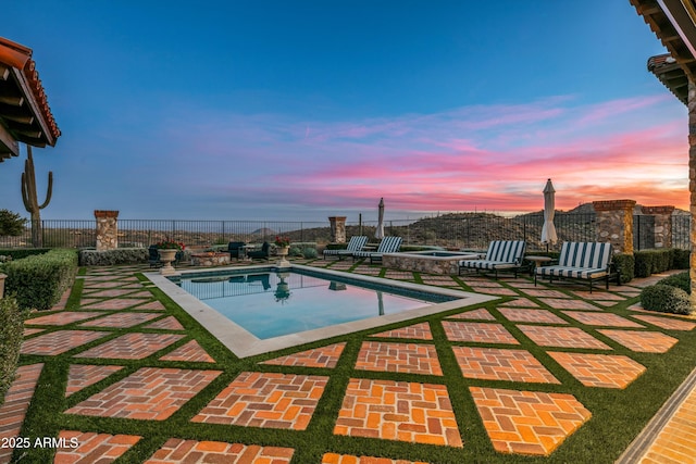 pool at dusk with an in ground hot tub and a patio