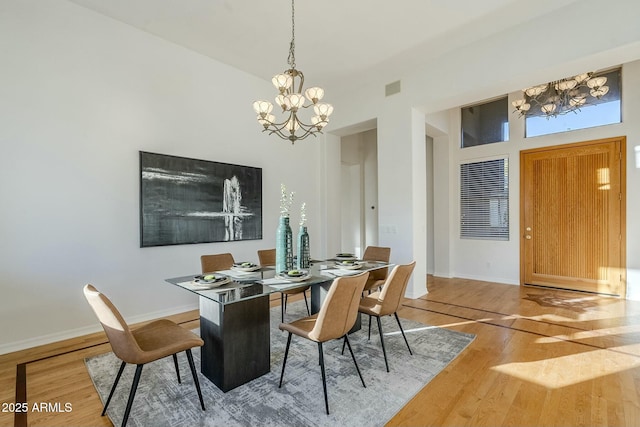 dining area featuring wood finished floors, visible vents, baseboards, and an inviting chandelier