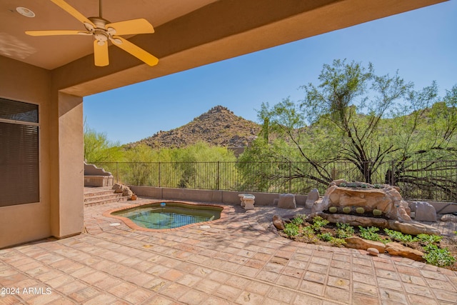 view of swimming pool featuring a patio area, a fenced backyard, a mountain view, and a ceiling fan