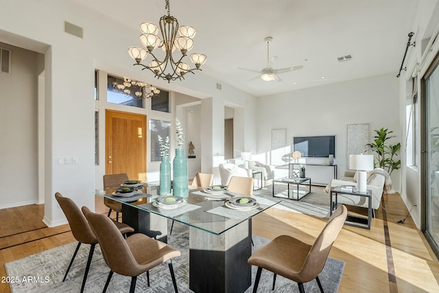 dining space with a chandelier, a wealth of natural light, visible vents, and light wood-style floors