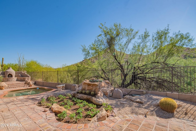 view of patio featuring an outdoor stone fireplace and fence