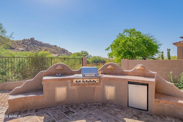 view of patio / terrace featuring a mountain view, an outdoor kitchen, and a grill