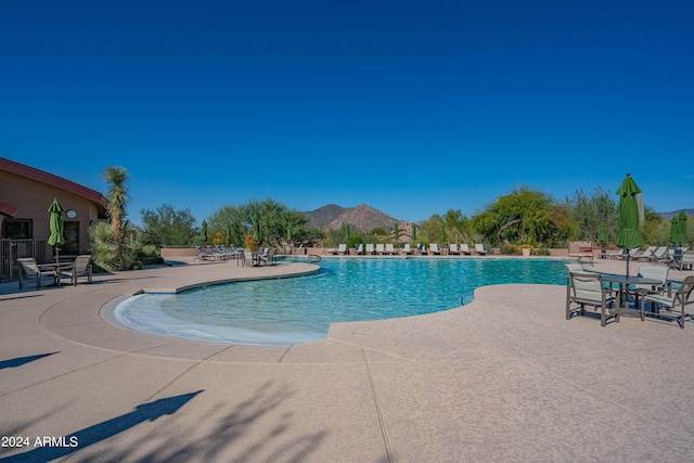 community pool with a mountain view and a patio