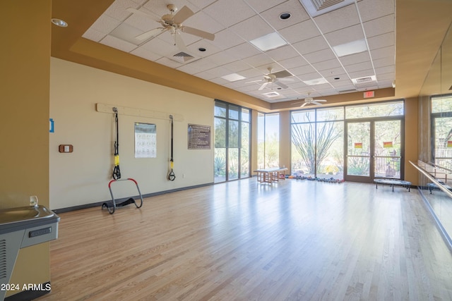 exercise area featuring a paneled ceiling, floor to ceiling windows, ceiling fan, and light hardwood / wood-style floors