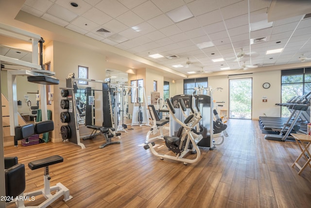 gym with a paneled ceiling, wood finished floors, and visible vents